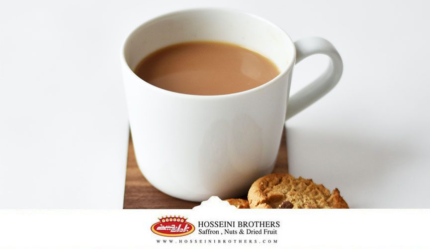 طرز تهیه چای ماسالا با شیر و خواص آن، یک فنجان چای ماسالا بر روی یک ظرف چوبی و یک عدد بیسکویت